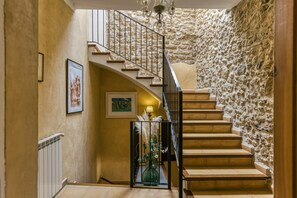 A staircase with a stone wall, a radiator, and framed artwork. - Holiday Home 'Ca La Maria' with Mountain Views, Private Terrace and Wi-Fi (Catalunya)