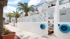 Un bâtiment blanc avec une porte blanche, une fenêtre bleue et un mur blanc orné de motifs en forme d’étoiles.