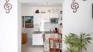 Une cuisine avec des meubles blancs, un four à micro-ondes et une machine à café rouge.