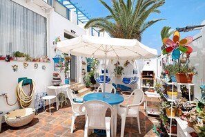 Eine Terrasse mit einem runden Tisch, weißen Stühlen und einer Hängematte.