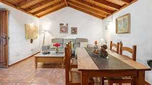Una habitación acogedora con techo de madera, un sofá, una mesa de comedor y una lámpara.