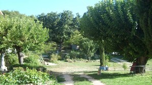 A rural setting with a dirt path leading through a garden area with trees and shrubs. - Durance Apartment with Terrace and Garden (Allemagne-En-Provence)