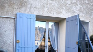 A blue door with a window, a stone wall, and a metal staircase. - Durance Apartment with Terrace and Garden (Allemagne-En-Provence)