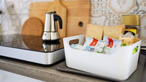 A kitchen counter with a coffee maker, a white basket containing bread and condiments, and a wooden cutting board. - Holiday Home 'Il Gattino Di Porto Appartamento 1' with Shared Pool, Wi-Fi and Air Conditioning (Imperia)