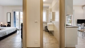 A modern hotel room with a bed, a desk, a mirror, and a view of the outside. - Holiday Home 'Il Gattino Di Porto Appartamento 2' with Shared Pool, Wi-Fi and Air Conditioning (Imperia)