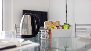 A breakfast setting with a kettle, bread, and condiments on a glass table. - Holiday Home 'Il Gattino Di Porto Appartamento 2' with Shared Pool, Wi-Fi and Air Conditioning (Imperia)