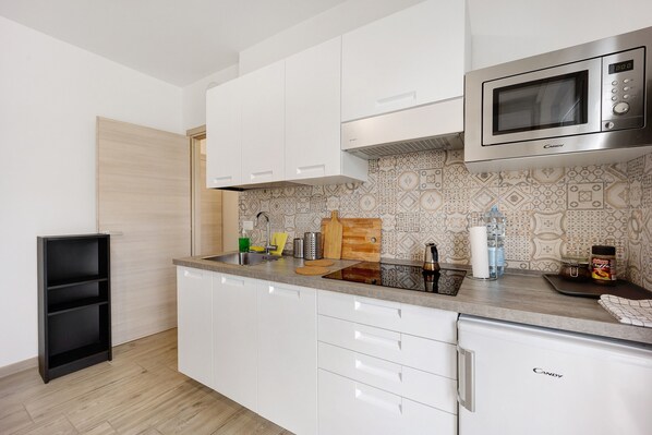 A modern kitchen with white cabinets, a microwave, and a sink.