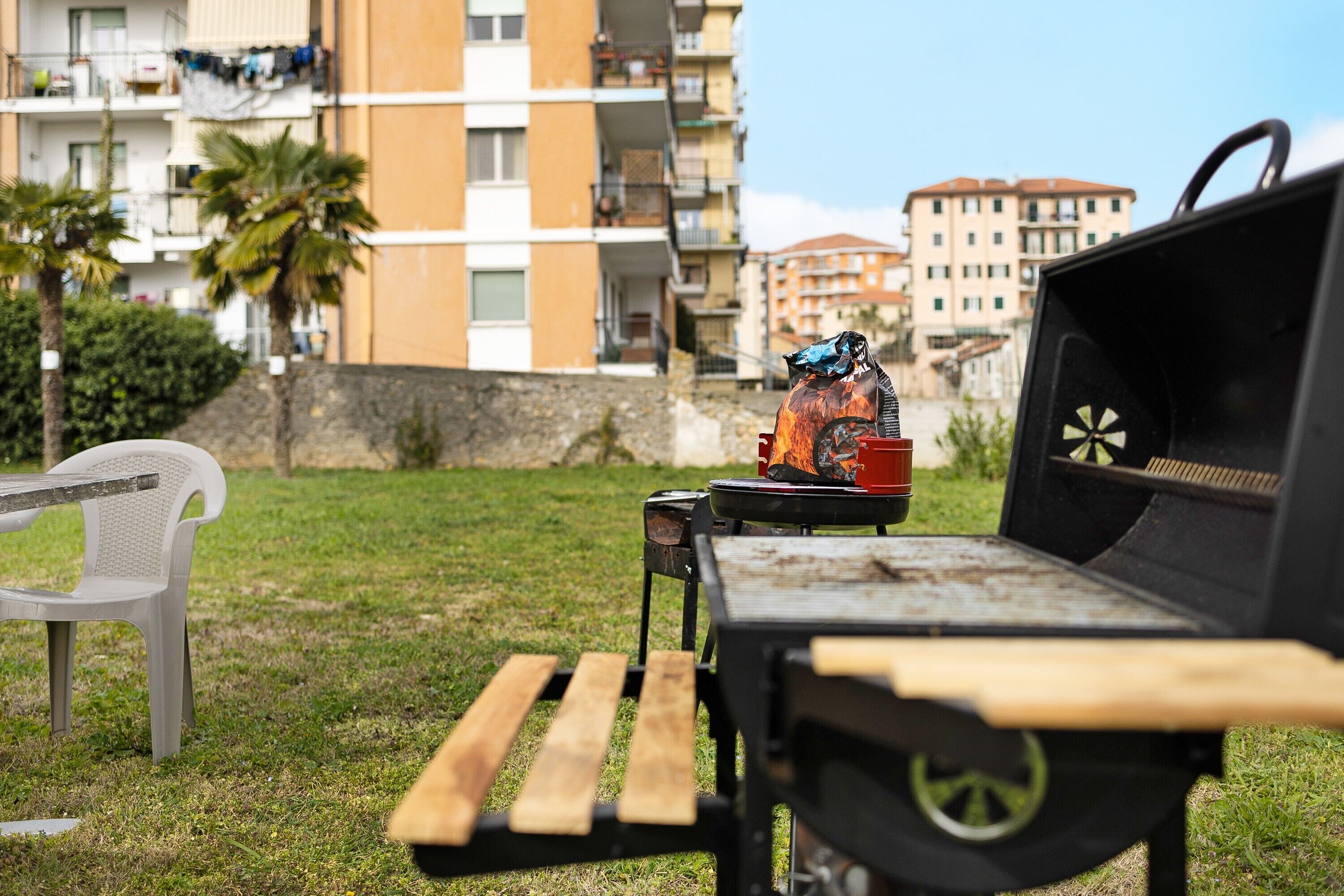 Una griglia per barbecue all'aperto con una sedia di plastica e un tavolo nelle vicinanze.