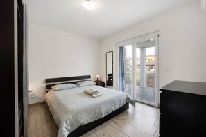 A bedroom with a bed, bedside tables, a mirror, and a sliding glass door leading to an outdoor area. - Holiday Home 'Il Gattino Di Porto Appartamento 2' with Shared Pool, Wi-Fi and Air Conditioning (Imperia)