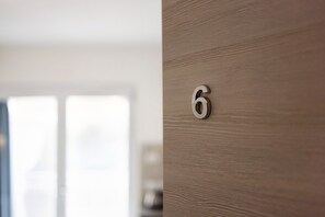 Primer plano de una puerta de madera con el número '6' de metal, indicando un número de habitación.