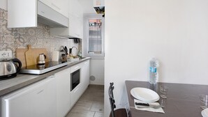 Une cuisine moderne avec des meubles blancs, une bouilloire en acier inoxydable et un plan de travail.