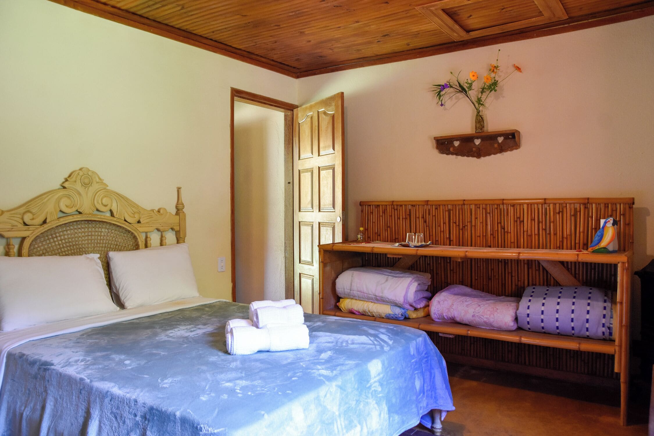 Une chambre à coucher avec un lit, une tête de lit en bois, une étagère avec des serviettes et une étagère murale décorée de fleurs.