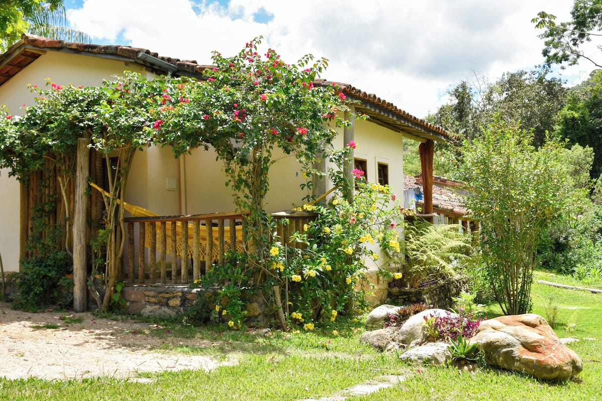 Ein Haus mit Garten, einer Holzveranda und einer Steinmauer.