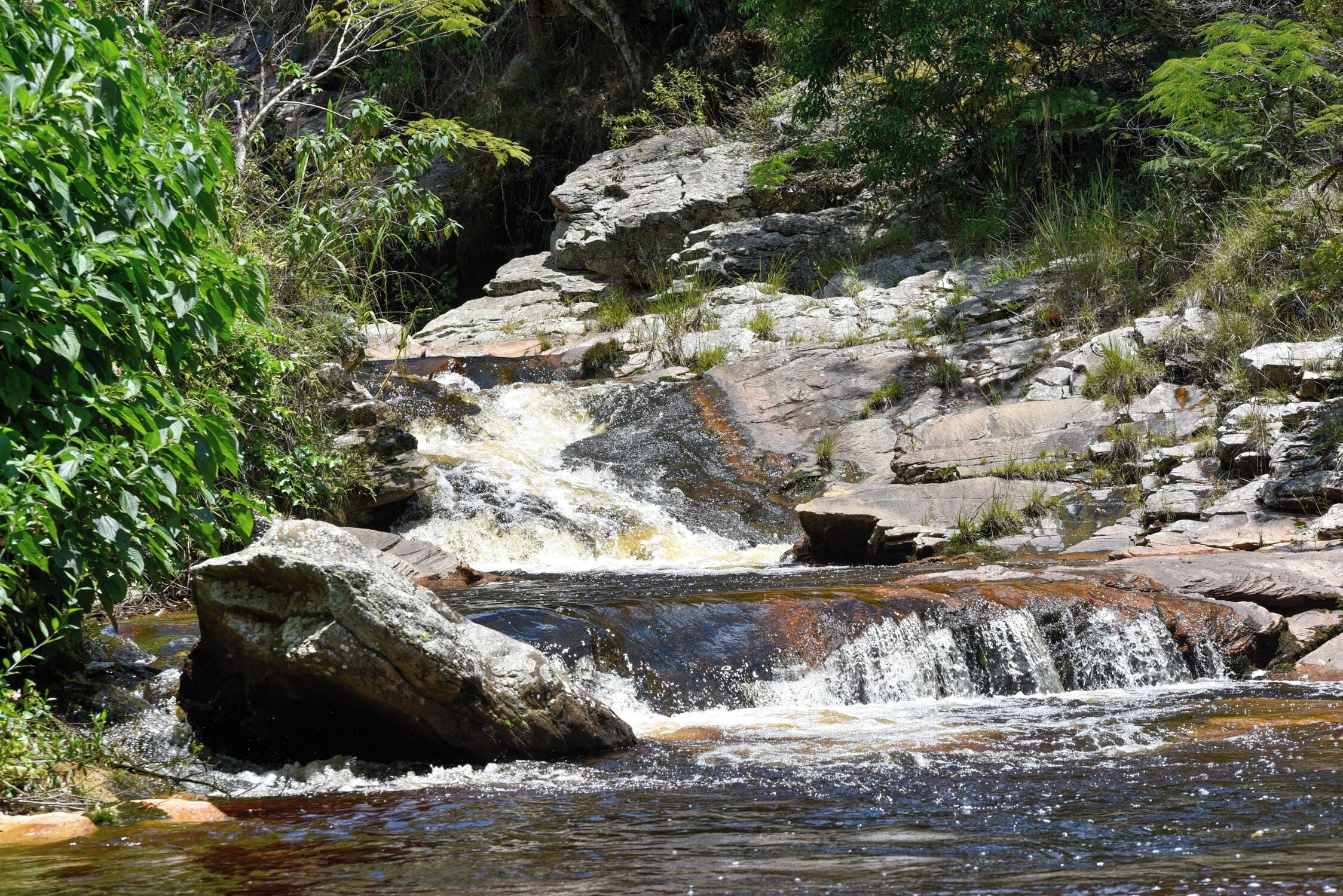 A natural waterfall surrounded by rocks and greenery.