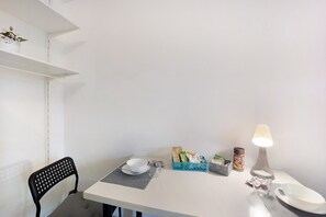 A dining area with a table, chairs, a lamp, and various food items.