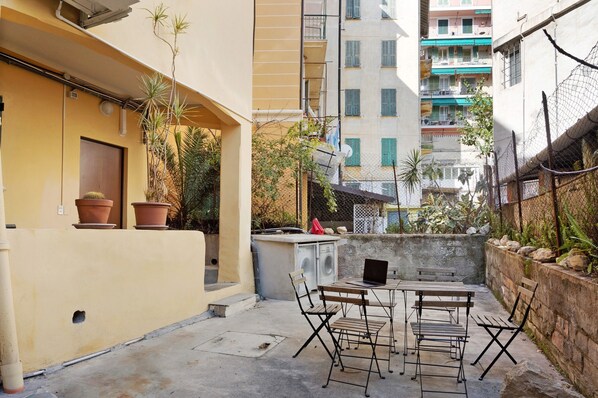 A courtyard with a seating area, a washing machine, and potted plants.