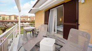 A balcony with outdoor furniture, a sliding glass door, and a view of neighboring buildings. - Holiday Home 'Il Gattino Di Porto Appartamento 4' with Shared Pool, Wi-Fi and Air Conditioning (Imperia)