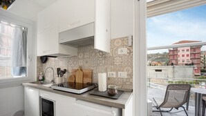 A modern kitchen with white cabinets, a built-in oven, and a window overlooking a cityscape. - Holiday Home 'Il Gattino Di Porto Appartamento 4' with Shared Pool, Wi-Fi and Air Conditioning (Imperia)