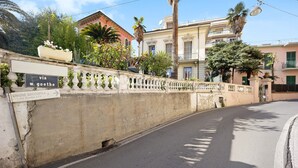 Een straat met een bochtige weg, een witte balustrade en een bord met de tekst 'via W. Goethe'.
