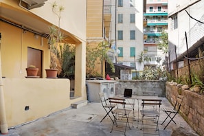 A courtyard with a seating area, a washing machine, and potted plants.