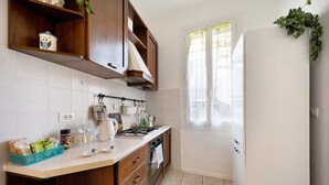 Een keuken met houten kastjes, een gasfornuis en een raam met gordijnen.