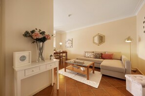 A living room with a sofa, coffee table, and a vase of flowers. - Apartment 'Sol Do Atlântico' with Shared Pool, Wi-Fi and Air Conditioning (Portimão)