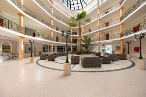 A multi-level atrium with a central palm tree, seating areas, and a tiled floor. - Apartment 'Sol Do Atlântico' with Shared Pool, Wi-Fi and Air Conditioning (Portimão)