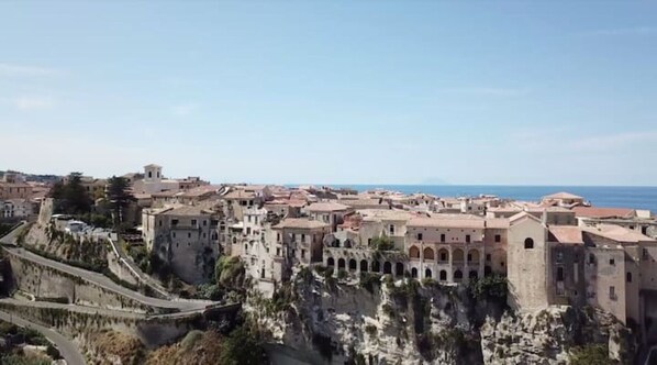 A coastal town with historic architecture, a prominent fortress, and a clear view of the sea.
