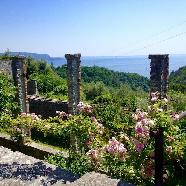 A stone structure with a view of the sea and lush greenery.