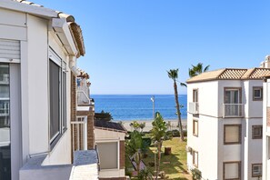 Un edificio sul lungomare con vista sul mare, un balcone e un piccolo giardino con palme.