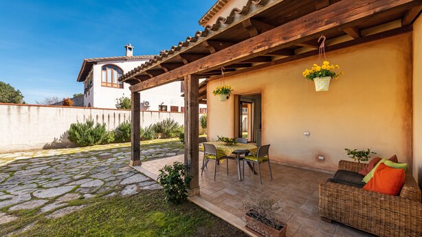 A patio with a table and chairs, a wicker sofa, hanging flower baskets, and a stone-tiled floor. - Holiday Home 'Girasole' with Private Terrace, Garden and Air Conditioning (Pula)