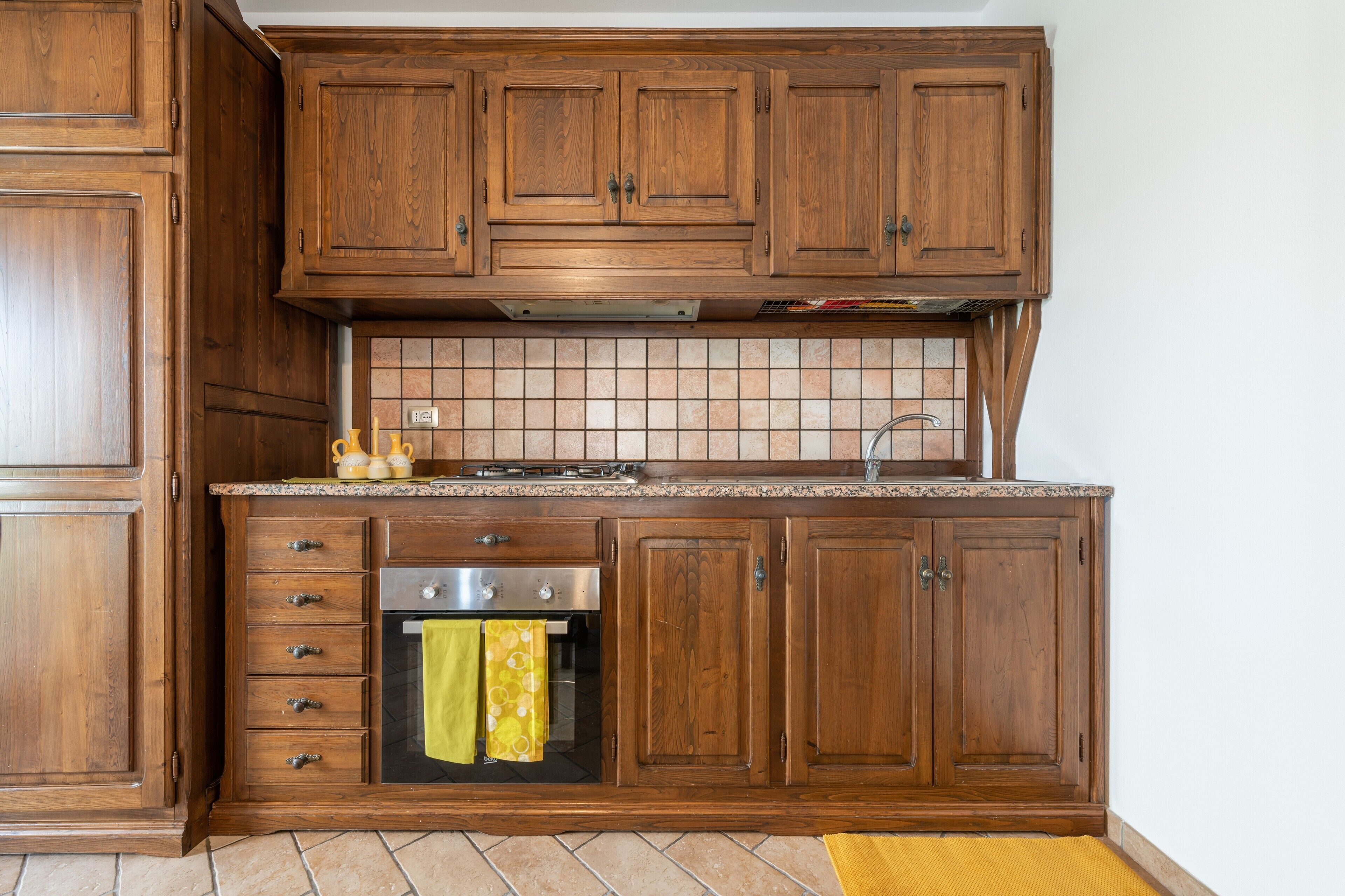 A kitchen with wooden cabinets, a built-in oven, and a tiled backsplash.
