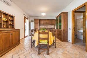 A dining area with a table set for four, surrounded by wooden cabinets and a kitchen in the background.