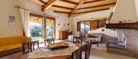 Un comedor con una mesa de madera, sillas, un sofá amarillo y una chimenea.
