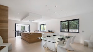 Eine moderne Küche mit einem Glastisch, weißen Stühlen und einer Wand mit Holzakzenten.