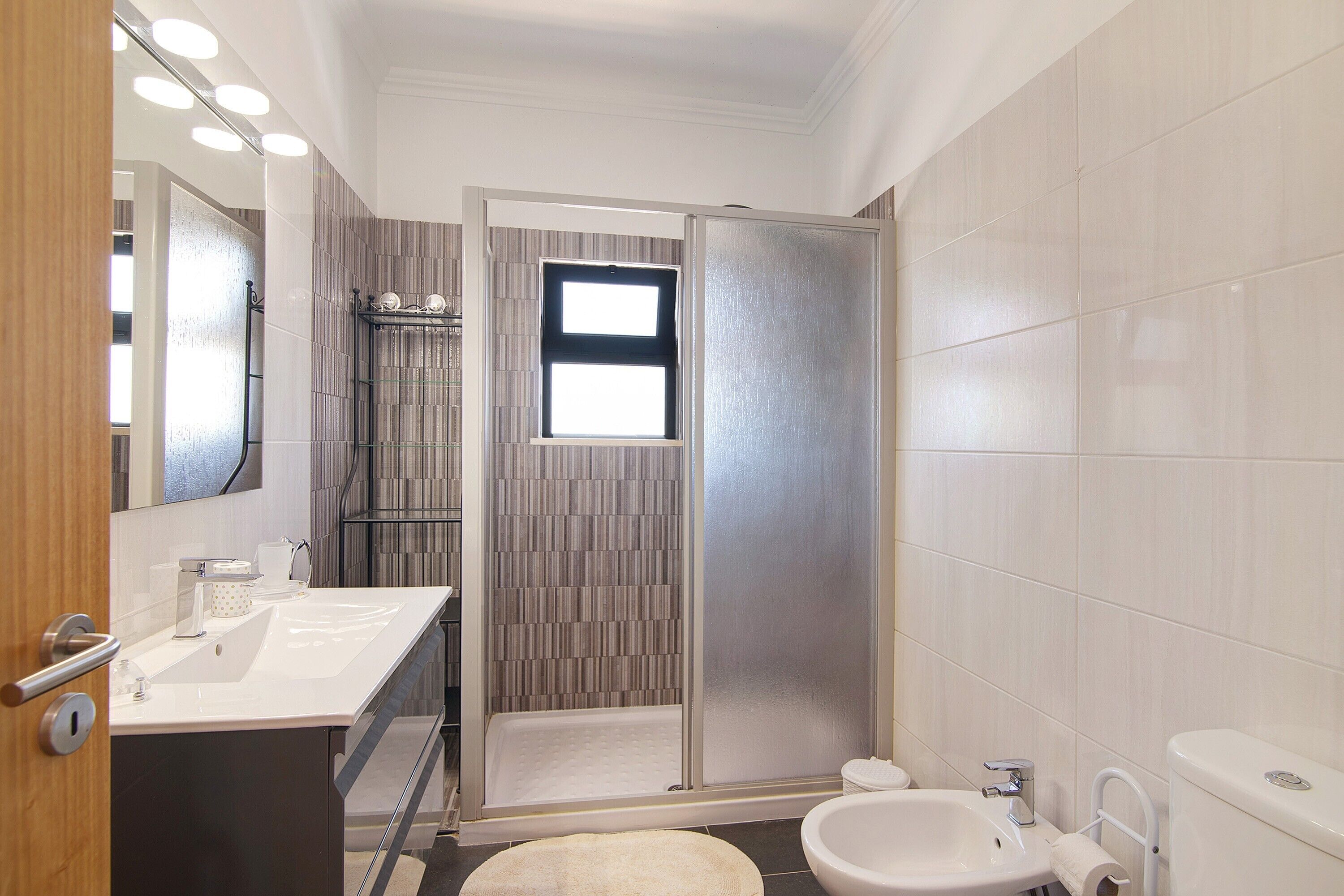 Une salle de bain moderne équipée d’une douche, de toilettes, d’un lavabo et d’un grand miroir.