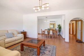 A living room with a sofa, coffee table, and dining area with chairs and a table.