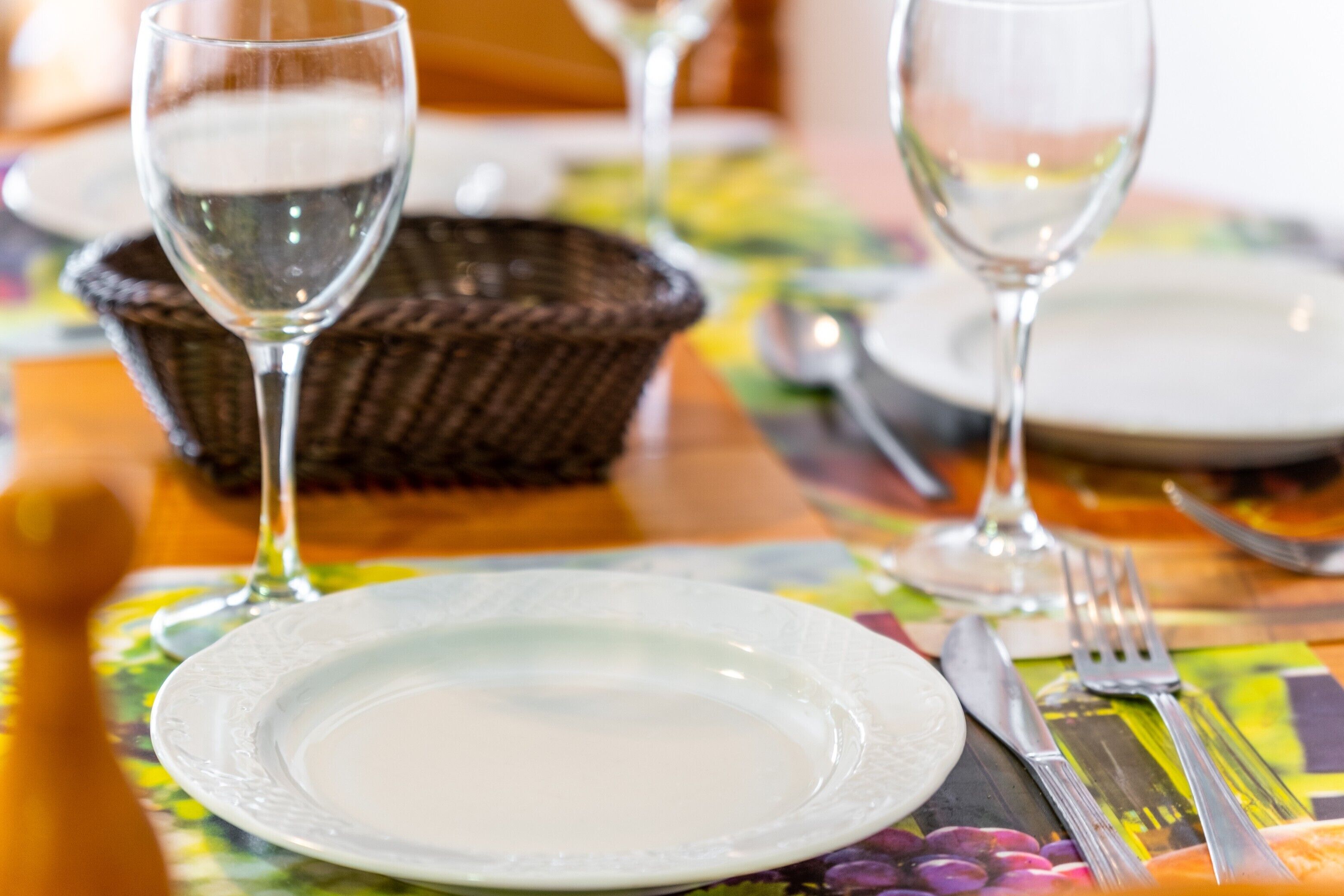 A dining table with a white plate, a glass of water, and cutlery.