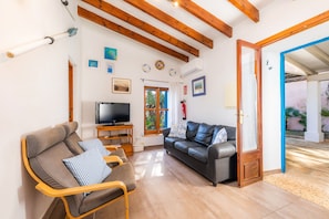 Een woonkamer met een bank, stoelen, een televisie en een houten plafond.