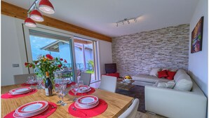 Een eetgedeelte met een houten tafel gedekt voor vier personen, een vaas met bloemen en uitzicht op de omgeving.