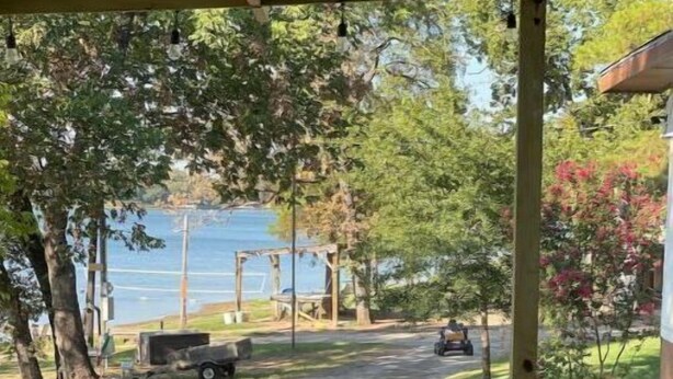 A wooden deck leading to a covered area with a view of a road and a body of water. - Lakefront with Private Dock & Sandy Shore (Malakoff)