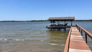 A wooden pier extending into calm water with a covered seating area and a clear sky. - Lakefront with Private Dock & Sandy Shore (Malakoff)
