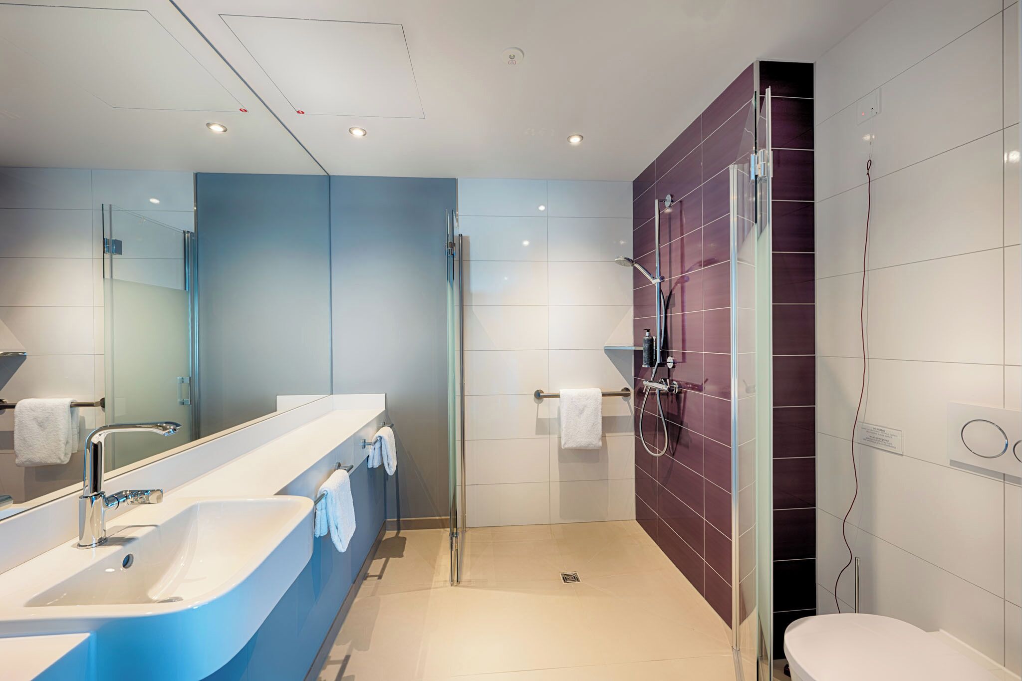 Een moderne badkamer met een grote spiegel, een badkuip, een douche en een toilet.