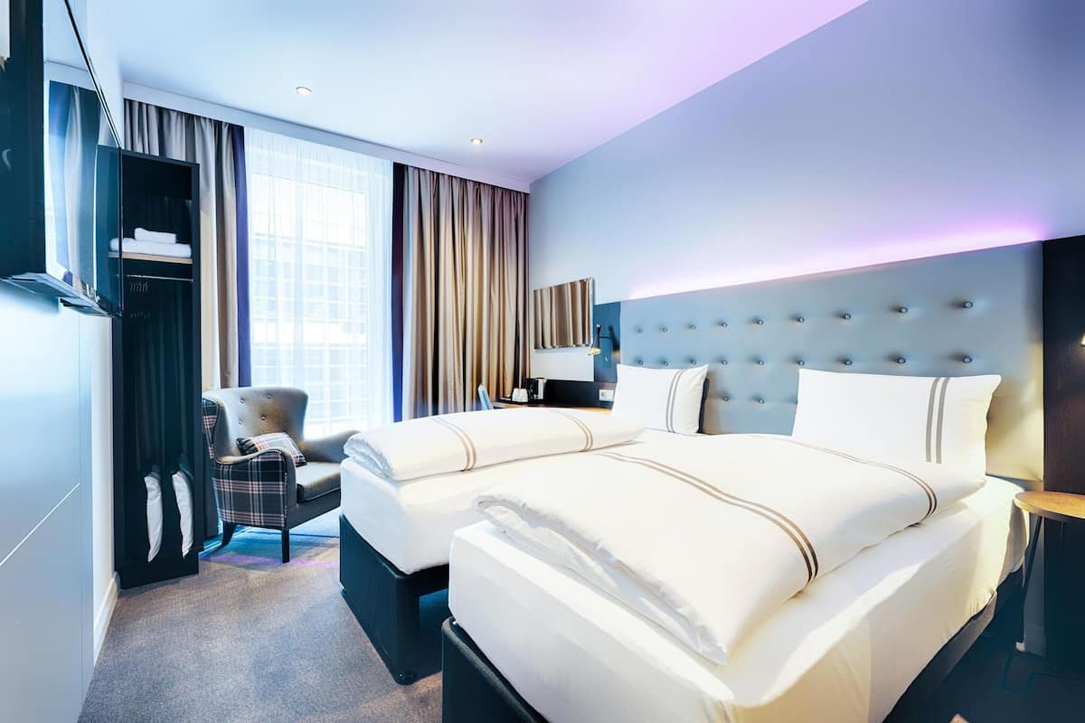 Une chambre d’hôtel avec un grand lit, une chaise, une télévision et une armoire.