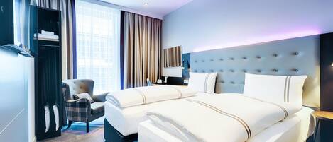 Una habitación de hotel con una cama grande, una silla, un televisor y un armario.