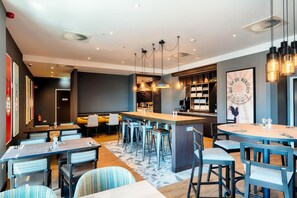 A modern hotel lobby with a bar area, seating arrangements, and a decorative wall. - Premier Inn Dresden City Prager Straße (Dresden)