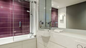 Ein modernes Badezimmer mit einer ein Glas umschlossenen Dusche, einem weißen Waschbecken und einem großen Spiegel.