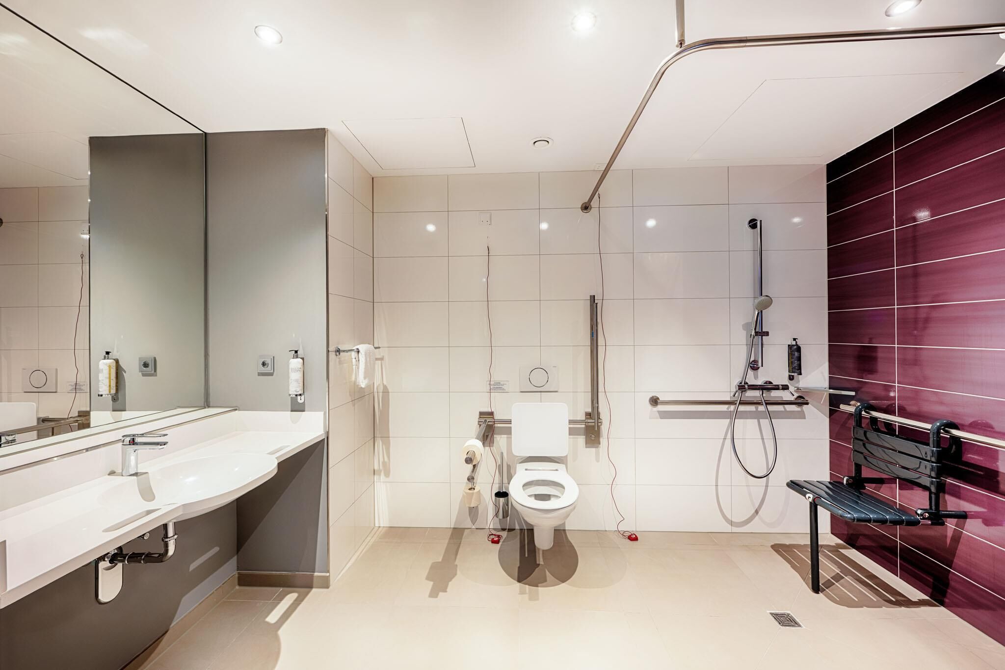 A modern bathroom with a large mirror, a sink, a toilet, and a shower.