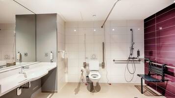 A modern bathroom with a large mirror, a sink, a toilet, and a shower.