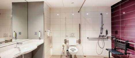 Un baño moderno con un espejo grande, lavamanos, inodoro y ducha.